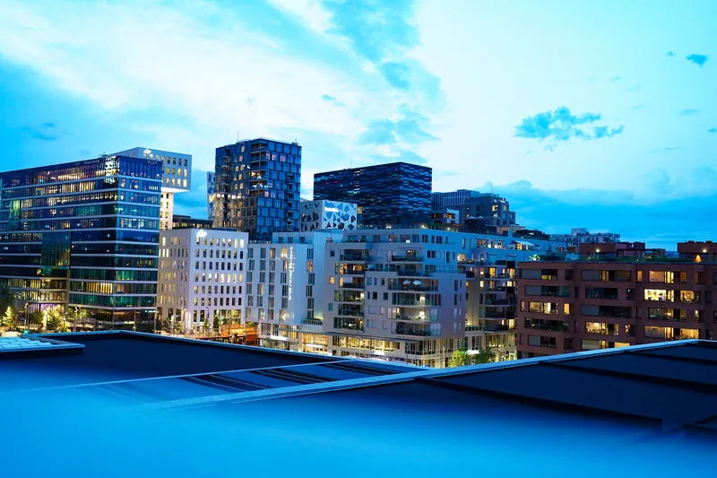 Kontor- og boligbyggene i Bjørvika i Oslo med lys i vinduene i skumringen