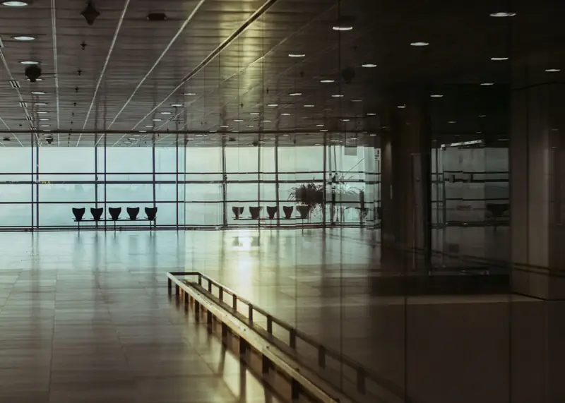 En tom flyplassterminal med glassfasade og lave lys, sett innenfra