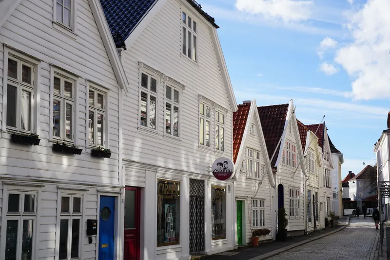 Hvite trehus med fargede ytterdører i en gate i Bergen