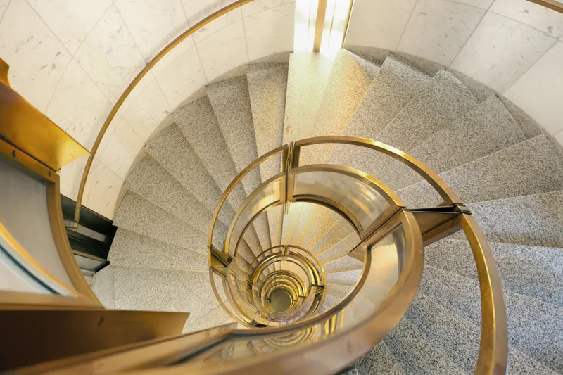 Spiraltrapp i granitt med messingrekkverk sett ovenfra, inne i Norges Banks hovedkontor