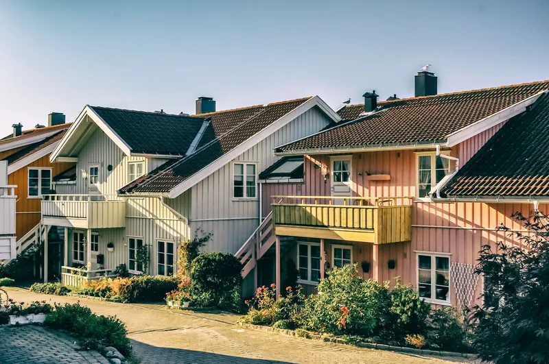 Pastellfargede trerekkehus med balkonger og små hager i lav ettermiddagssol