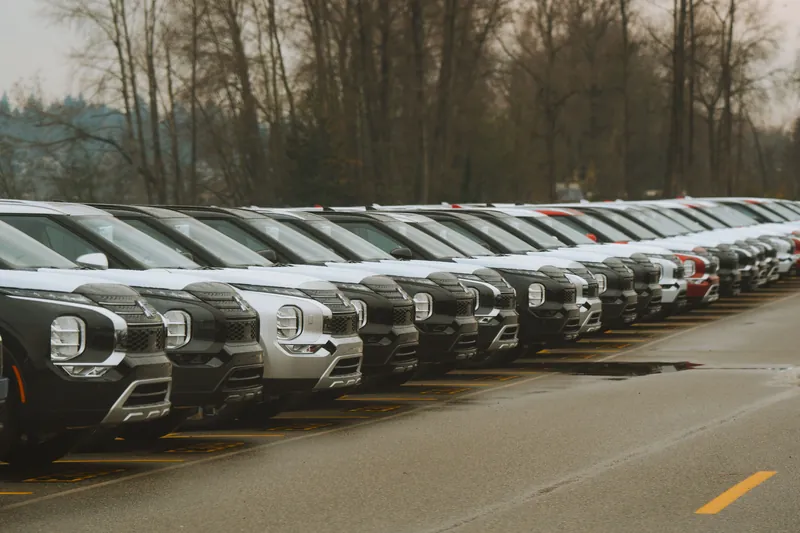 En lang rekke nye biler parkert side om side på en oppstillingsplass utendørs